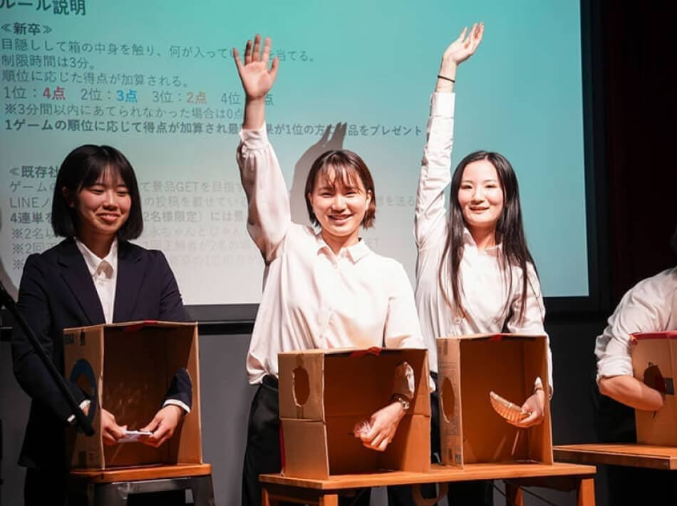 箱手を入れて中身を予想して楽しそうな新入社員の様子。